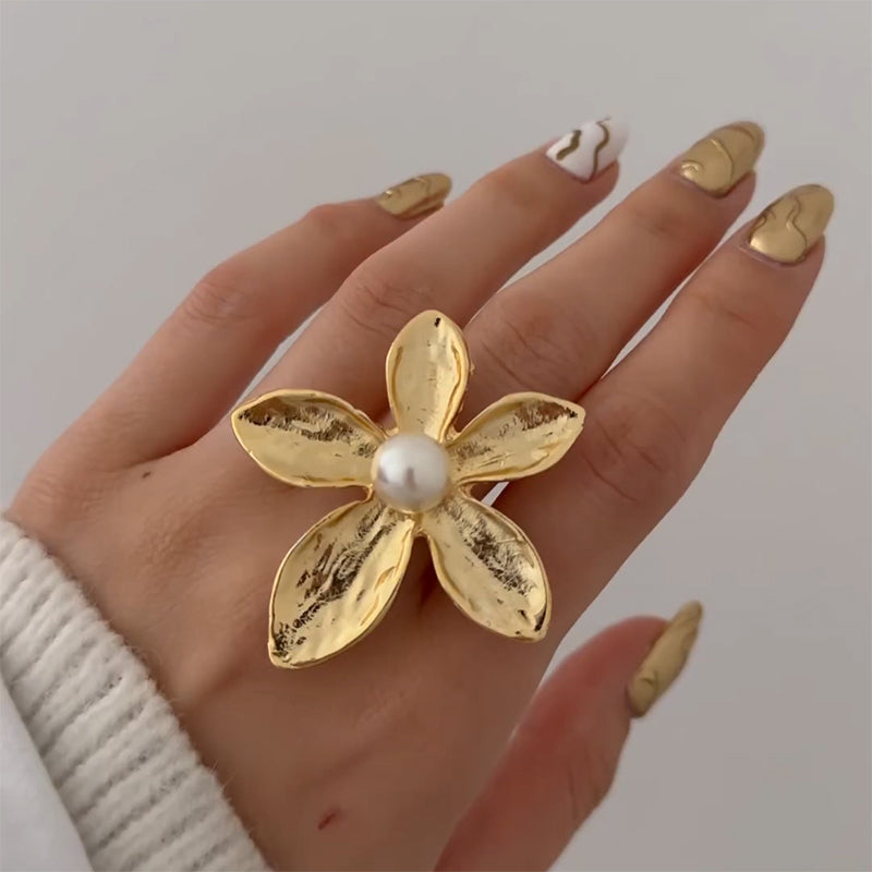 Gold flower-shaped ring with a central white pearl.