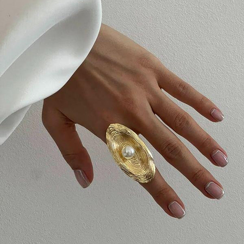 Gold spiral-shaped ring featuring a white pearl in the center.