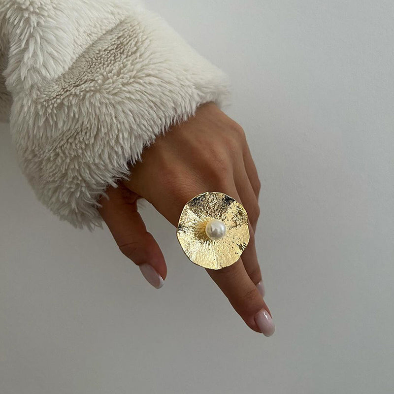 Gold circular-textured ring showcasing a white pearl in the center.