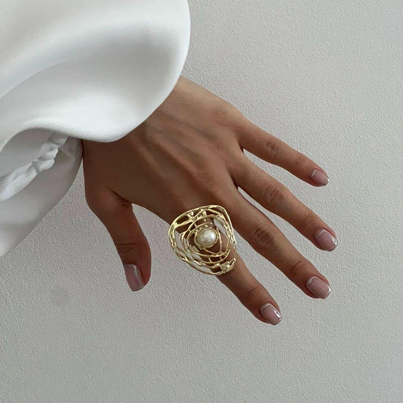 Gold swirling open-frame ring with a white pearl at the center.