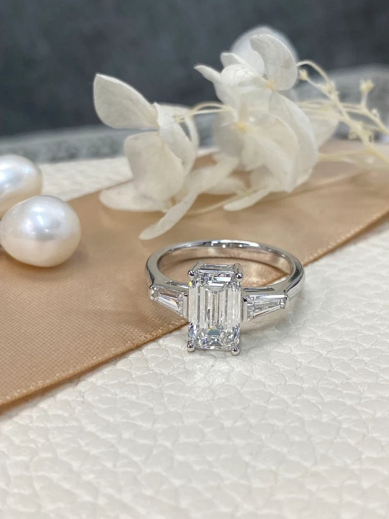 A minimalist three-stone emerald-cut lab-grown diamond ring with two dazzling side stones, set in 18K solid gold, perfect for engagements and weddings.