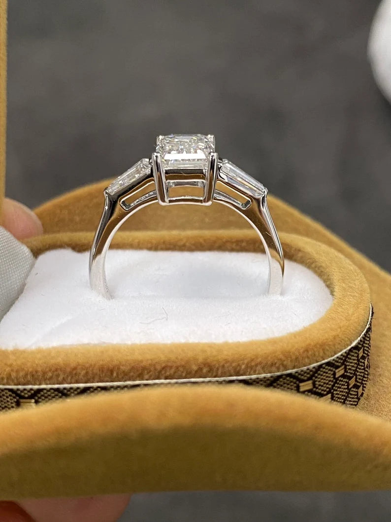 A minimalist three-stone emerald-cut lab-grown diamond ring with two dazzling side stones, set in 18K solid gold, perfect for engagements and weddings.