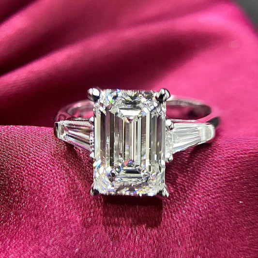 A minimalist three-stone emerald-cut lab-grown diamond ring with two dazzling side stones, set in 18K solid gold, perfect for engagements and weddings.